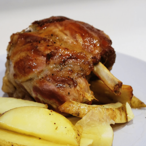 Codillo de cerdo asado con patata brava, zanahoria baby y judías
