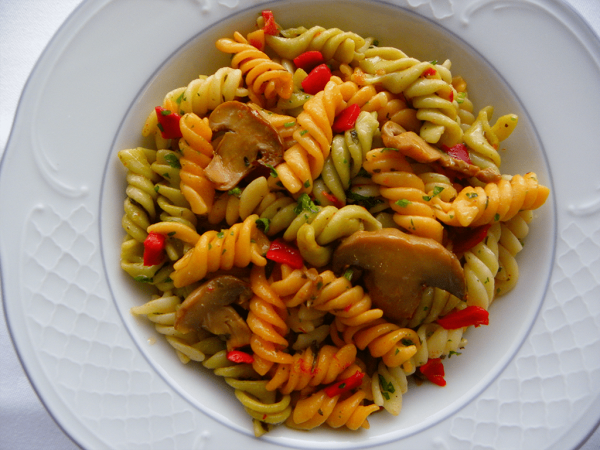 Espirales de pasta de color salteadas con verduras y champiñones